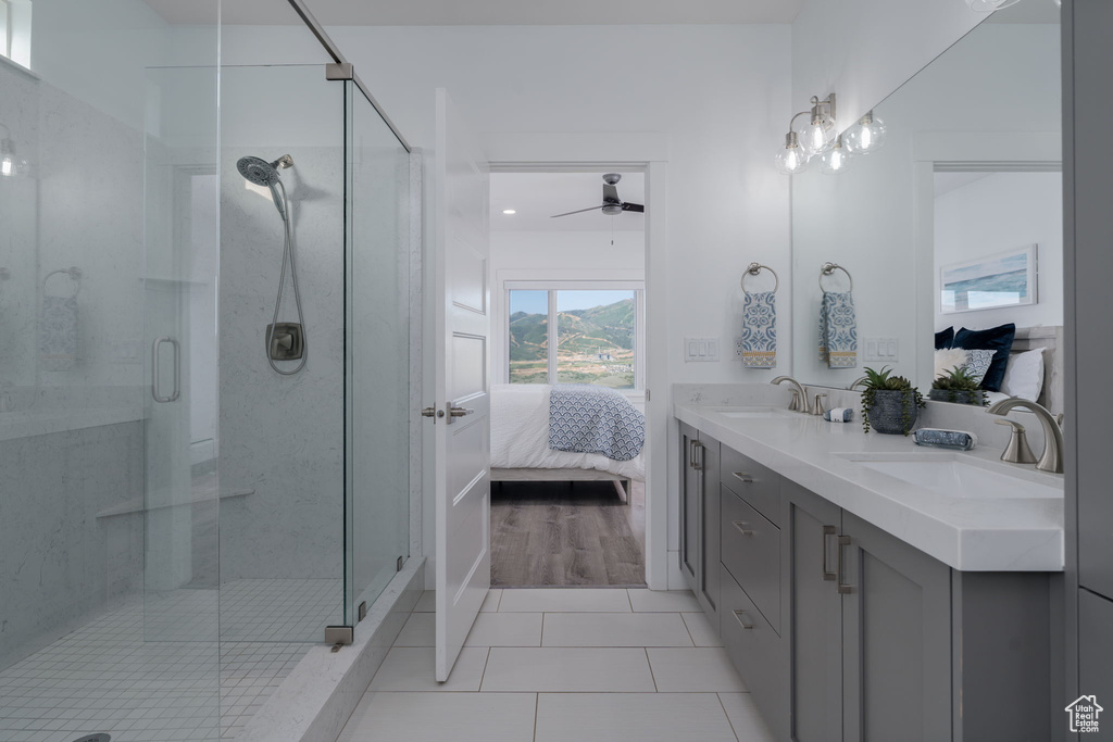 Ensuite bathroom with ceiling fan, double vanity, a shower stall, and tile patterned floors