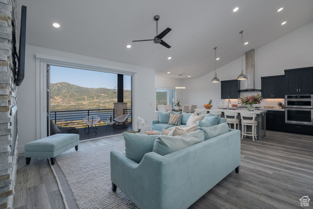 Living room with ceiling fan, high vaulted ceiling, wood finished floors, and recessed lighting