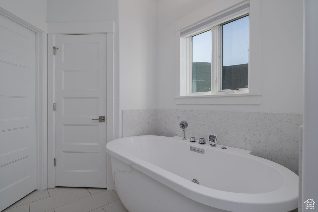 Full bath with a soaking tub and tile patterned flooring