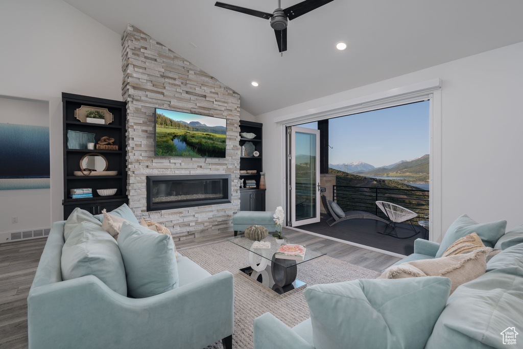 Living area featuring ceiling fan, wood finished floors, a stone fireplace, recessed lighting, and high vaulted ceiling