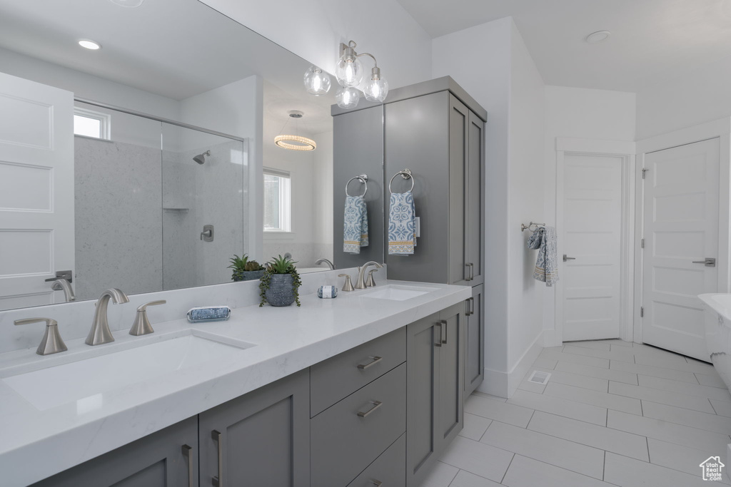 Bathroom with double vanity, walk in shower, and tile patterned flooring