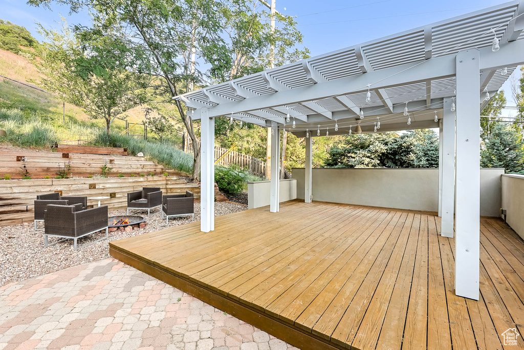 Wooden deck featuring a pergola and an outdoor living space with a fire pit