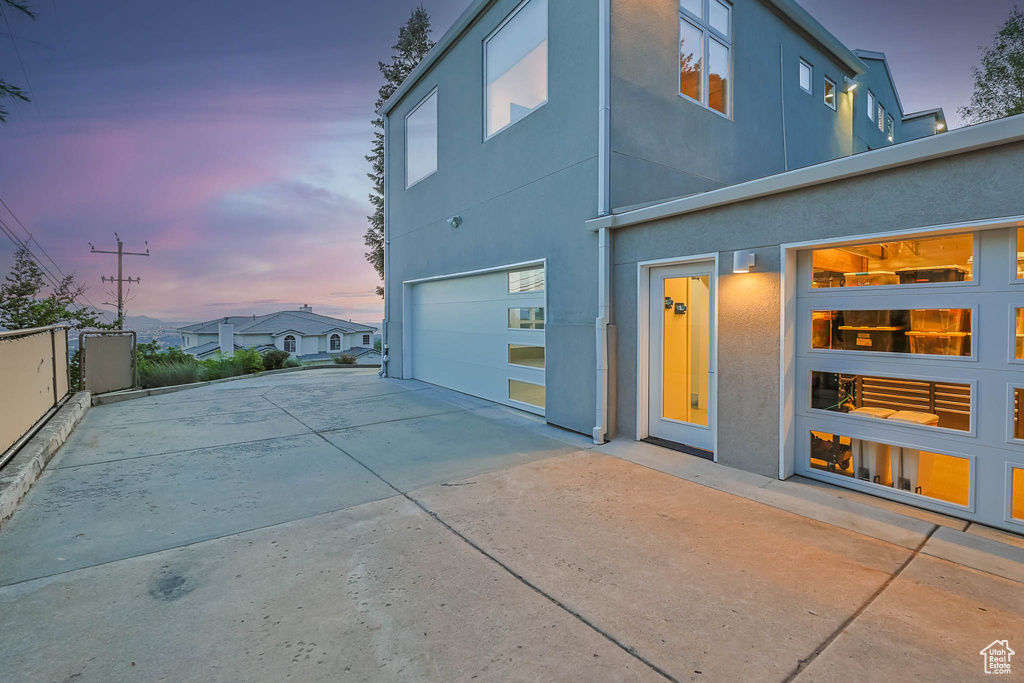 Back of house featuring concrete driveway, a garage, and stucco siding