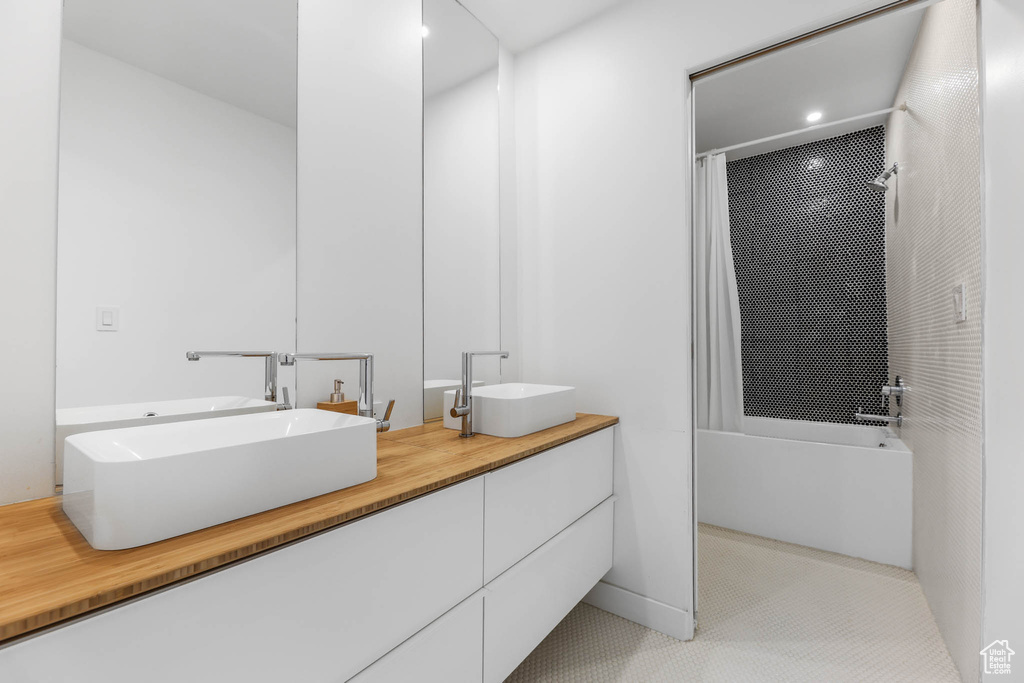 Full bath with shower / tub combo with curtain, double vanity, and tile patterned flooring