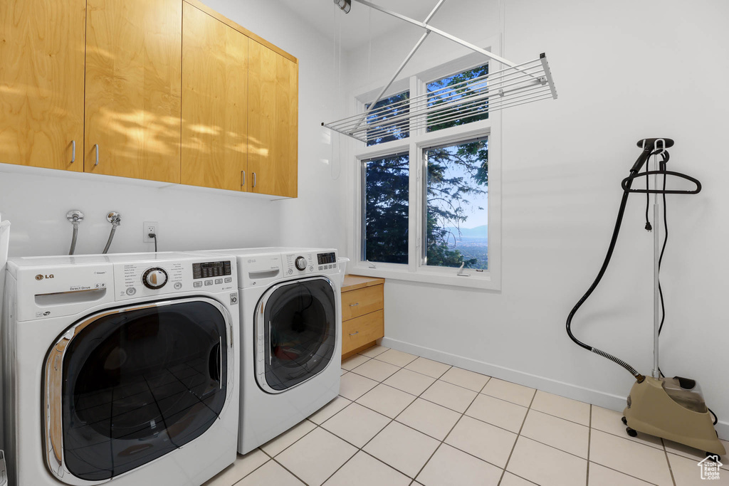 Laundry area with cabinet space, washer and clothes dryer, baseboards, and light tile patterned floors