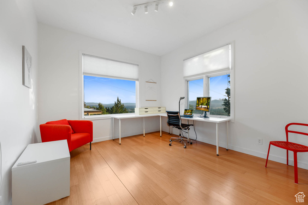 Home office with wood finished floors, rail lighting, and baseboards