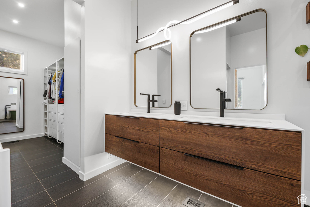 Bathroom with double vanity, a walk in closet, baseboards, tile patterned floors, and recessed lighting