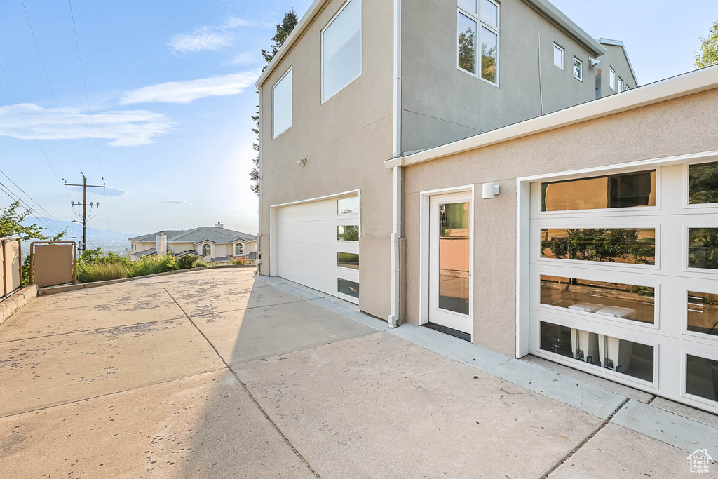 View of property exterior featuring concrete driveway, a garage, and stucco siding