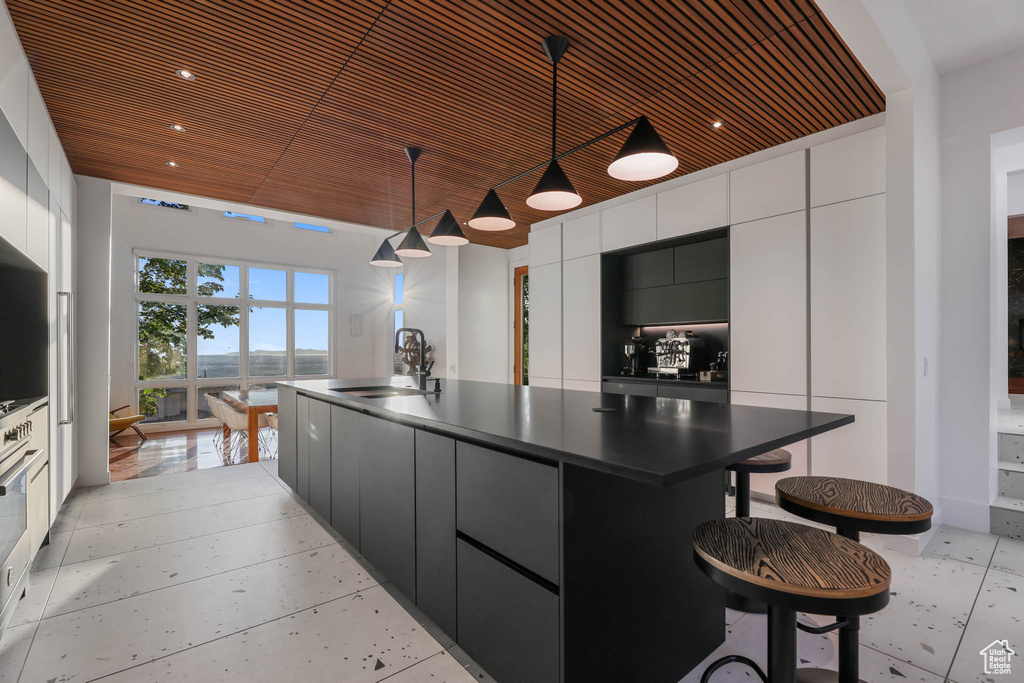 Kitchen featuring a sink, dark countertops, white cabinets, modern cabinets, and a kitchen island