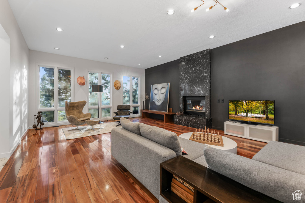 Living room featuring recessed lighting, hardwood / wood-style floors, a high end fireplace, and baseboards