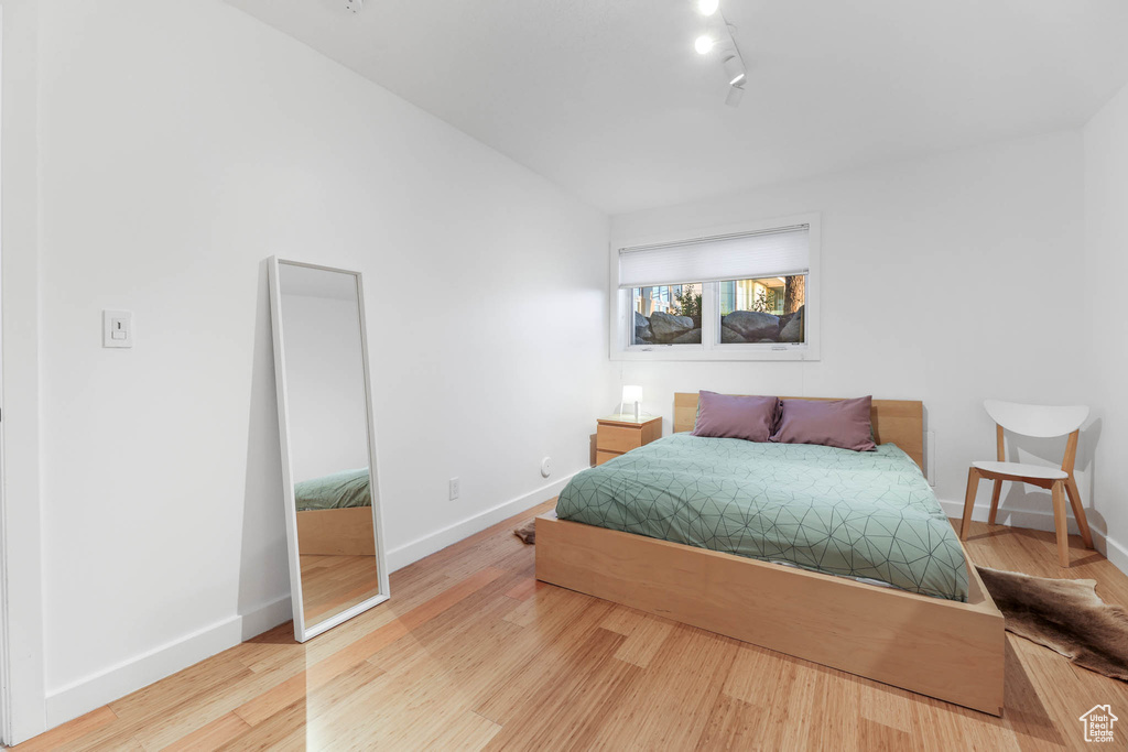 Bedroom featuring baseboards, wood finished floors, and rail lighting
