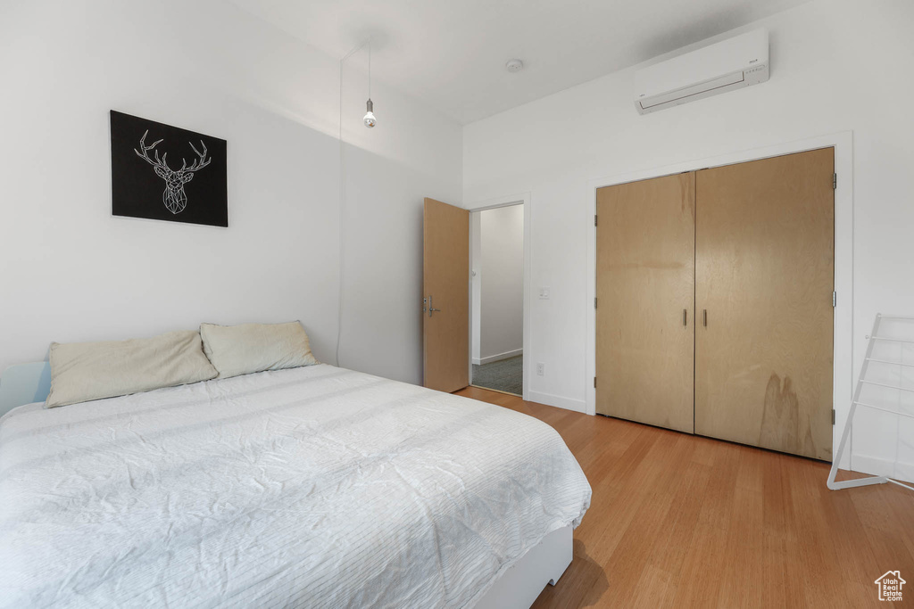 Bedroom featuring a wall mounted AC, light wood-style flooring, and a closet
