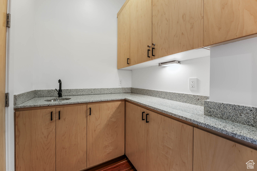 Kitchen featuring a sink, light stone counters, and light brown cabinets