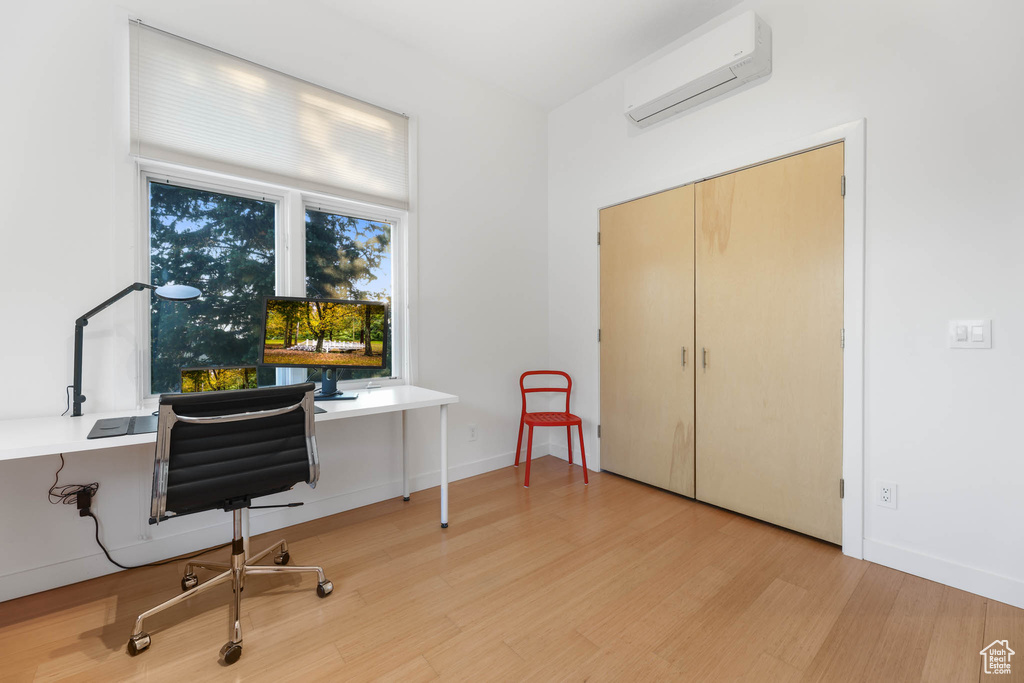 Office with a wall mounted air conditioner, wood finished floors, and baseboards