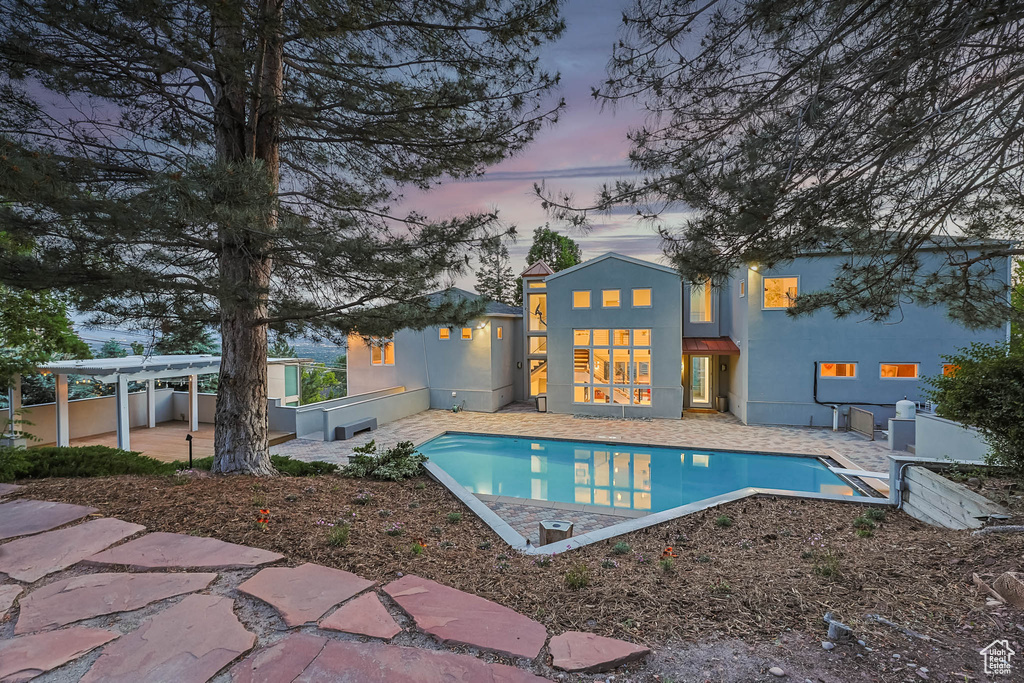 Pool at dusk with a patio area and an outdoor pool