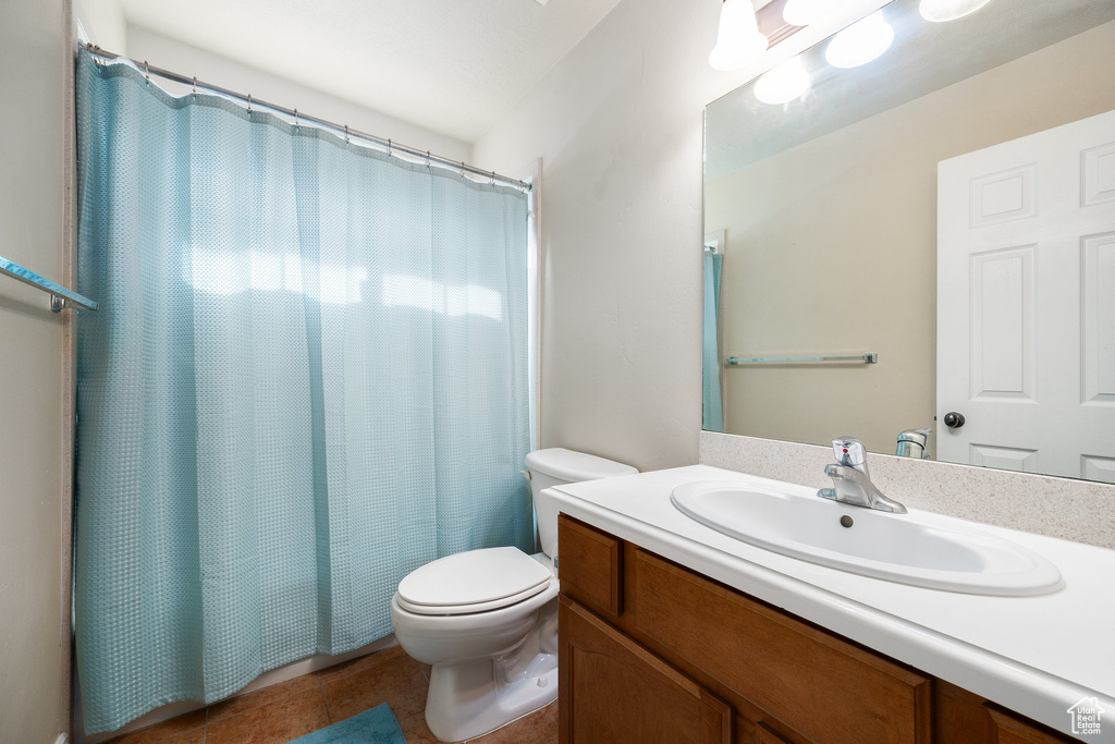Bathroom featuring vanity, toilet, a shower with shower curtain, and tile patterned floors