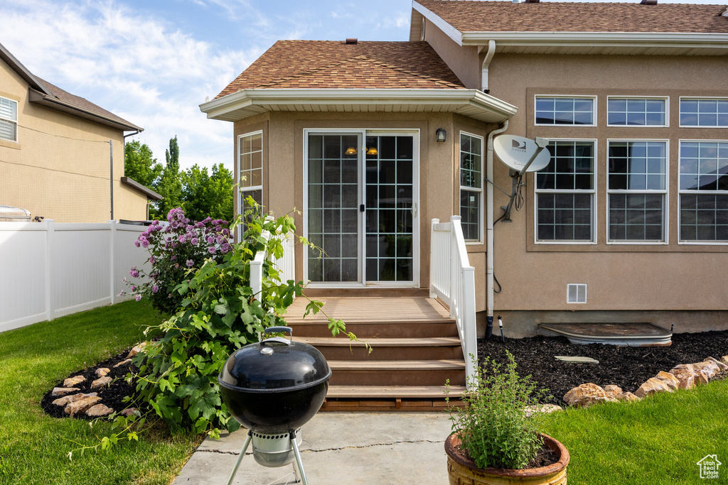 View of exterior entry featuring stucco siding and a shingled roof