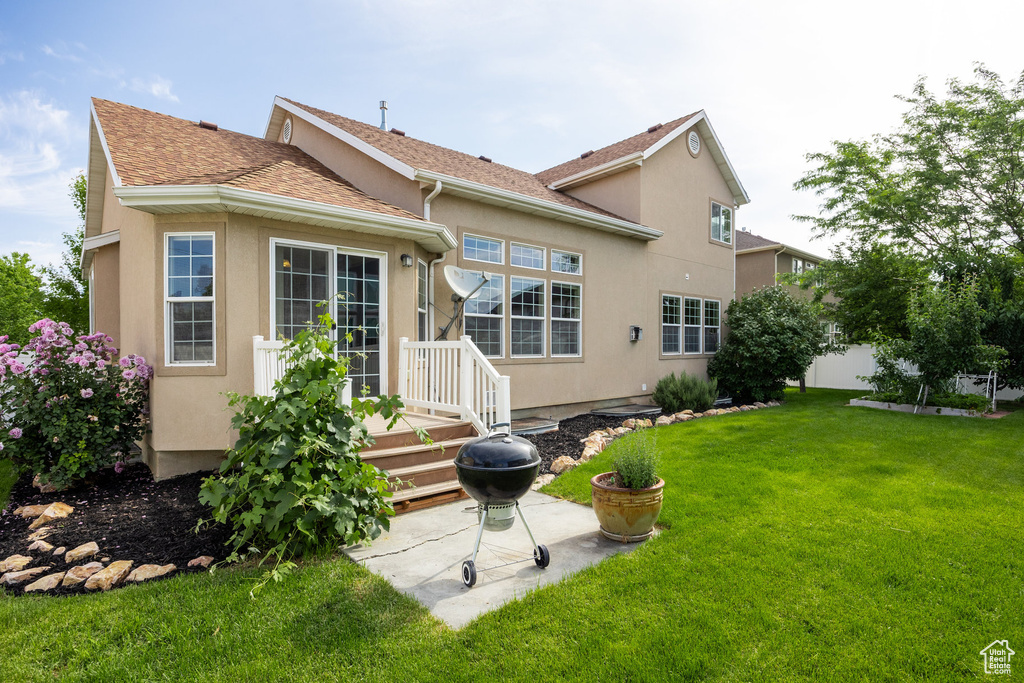 Back of house featuring stucco siding, a yard, a patio, and roof with shingles