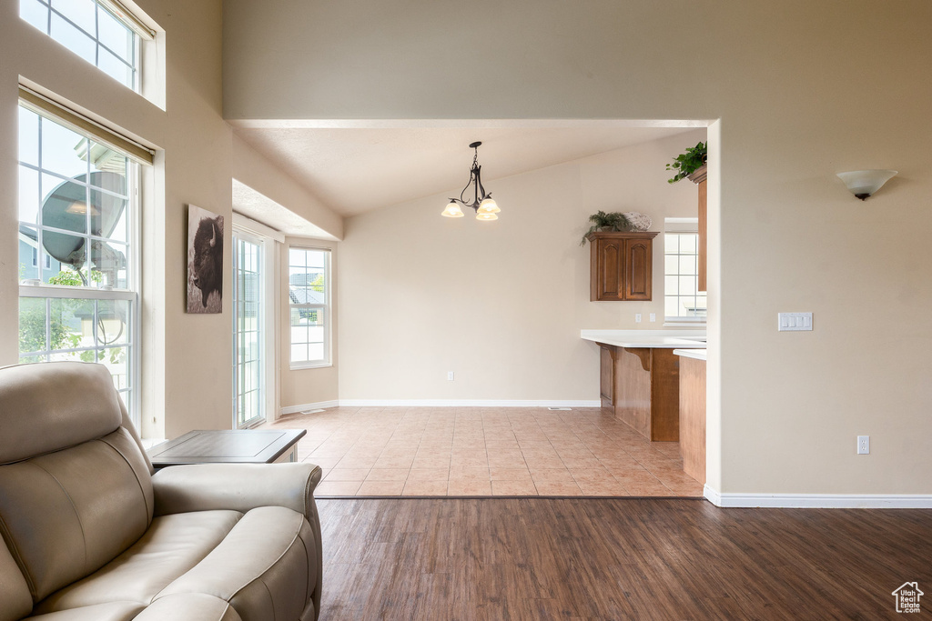 Living room featuring a chandelier, wood finished floors, baseboards, and lofted ceiling