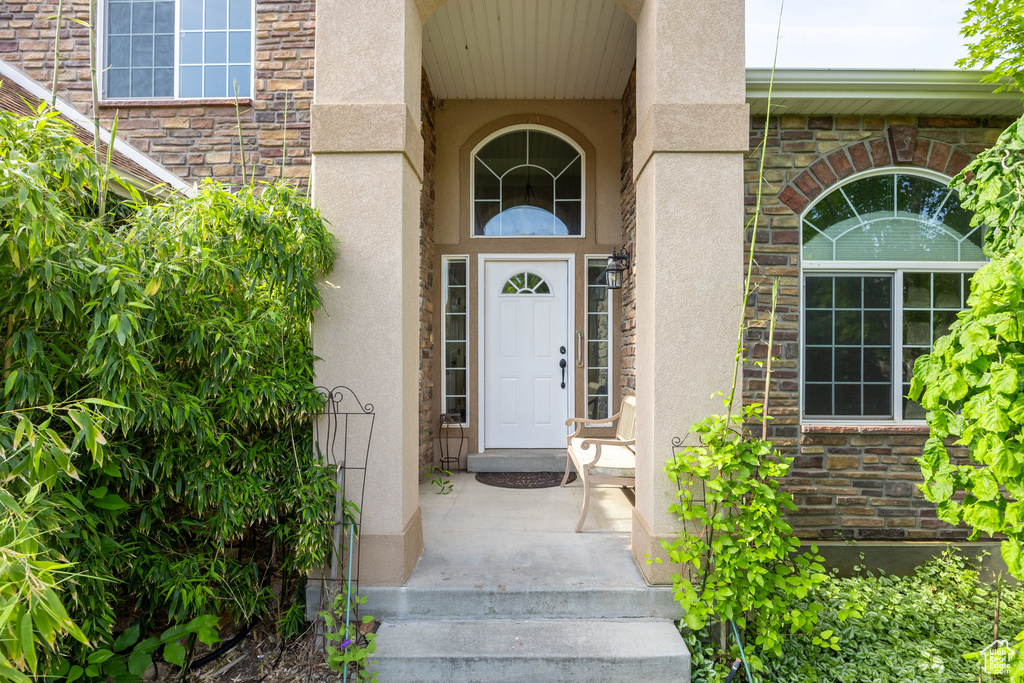 Doorway to property featuring stucco siding and stone siding