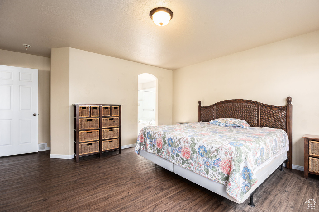 Bedroom featuring arched walkways, wood finished floors, and baseboards