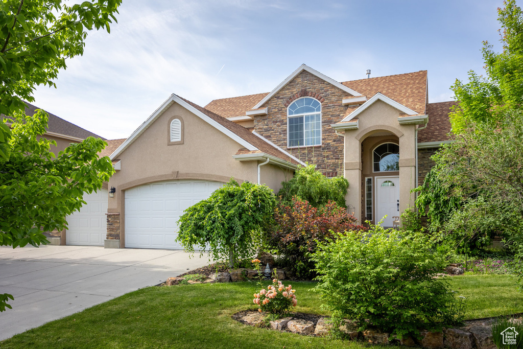 Traditional home with stucco siding, stone siding, and a front lawn