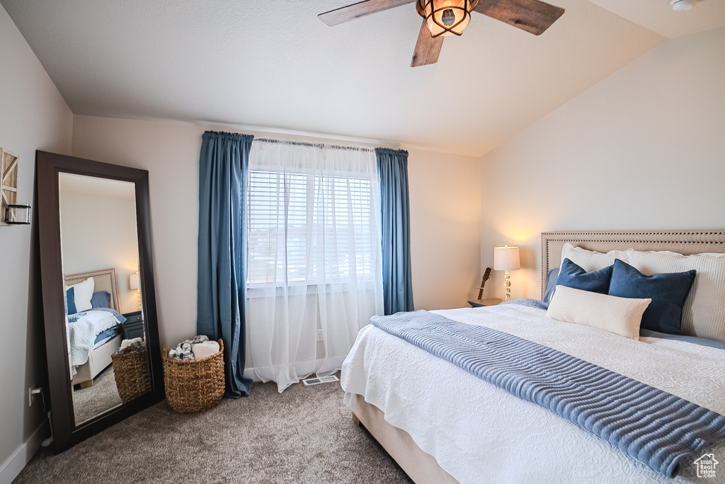 Bedroom featuring carpet, vaulted ceiling, and a ceiling fan