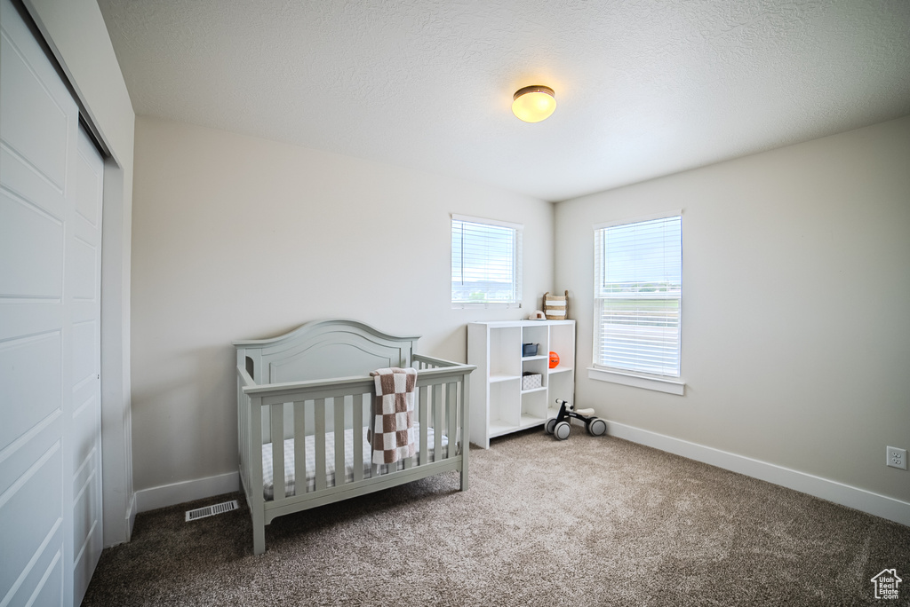 Bedroom featuring carpet floors, a closet, baseboards, and a nursery area