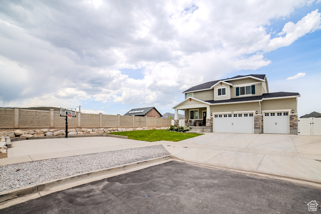 View of front of home with stone siding, an attached garage, concrete driveway, covered porch, and stucco siding