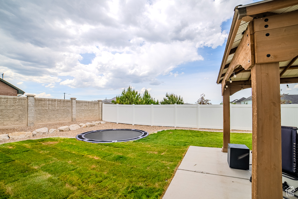 View of yard with a trampoline and a patio