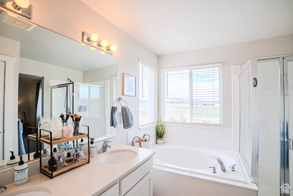 Bathroom featuring a bath, double vanity, and a stall shower