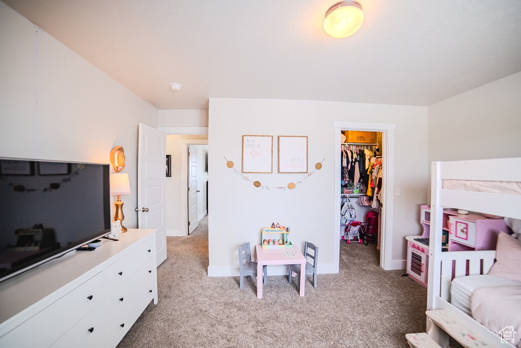 Bedroom featuring light carpet, a spacious closet, a closet, and baseboards