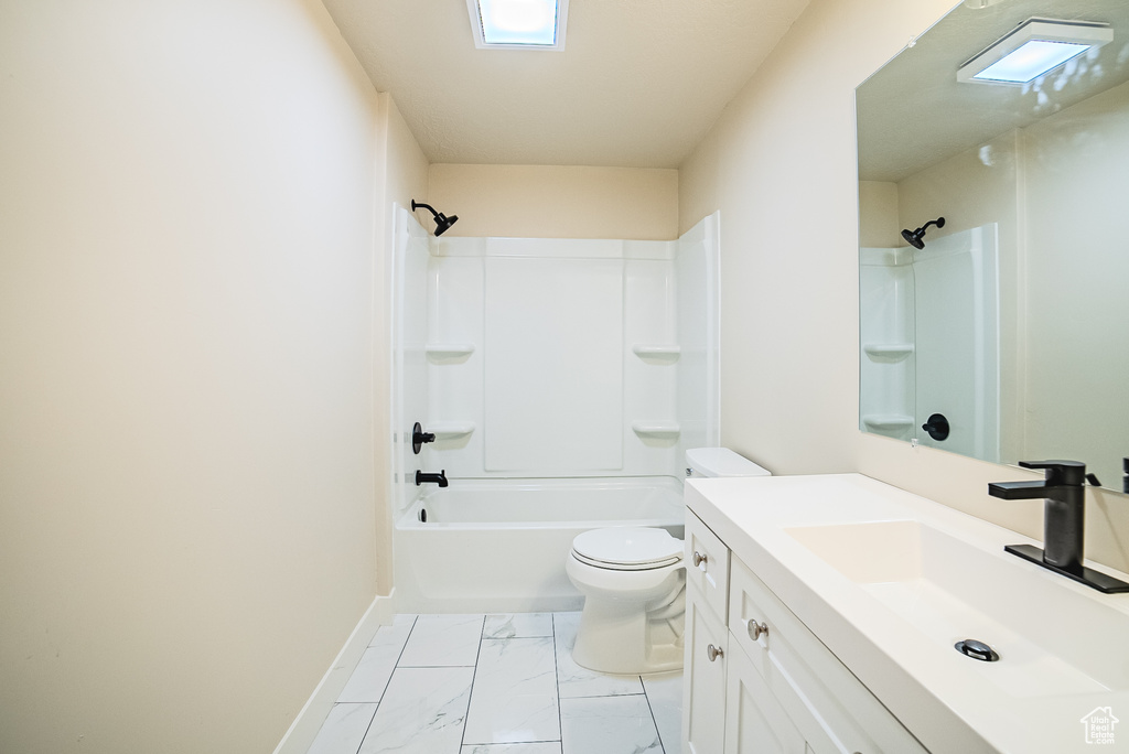 Bathroom with toilet, vanity, marble finish floors, bathtub / shower combination, and baseboards
