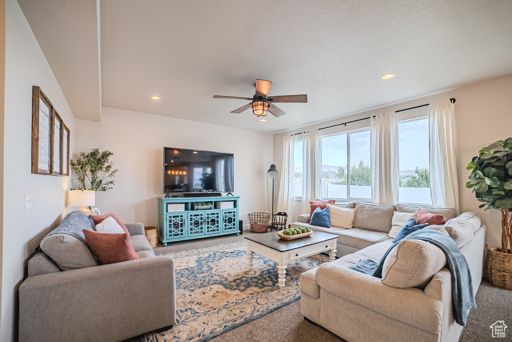 Carpeted living area with a ceiling fan and recessed lighting