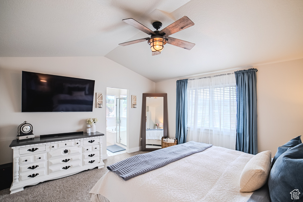 Bedroom featuring vaulted ceiling, carpet floors, ceiling fan, and ensuite bath