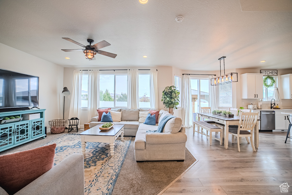 Living area with light wood-style flooring, a ceiling fan, and recessed lighting