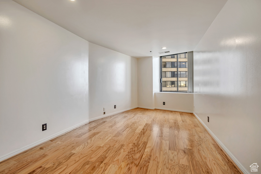 Empty room featuring wood finished floors, baseboards, and recessed lighting