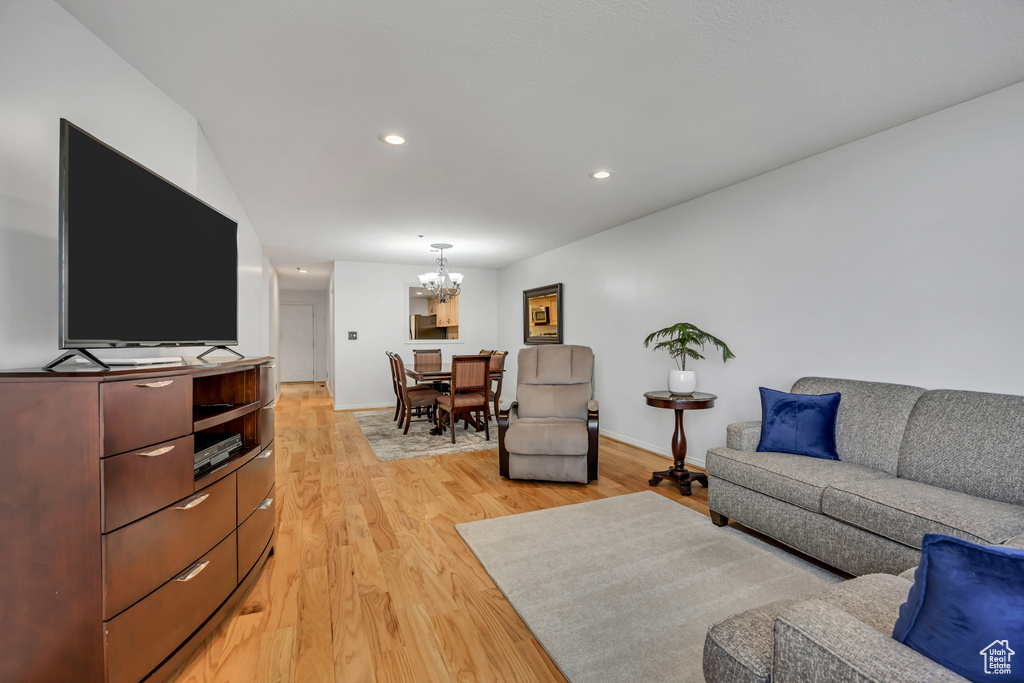 Living room featuring a chandelier, light wood-type flooring, recessed lighting, and baseboards