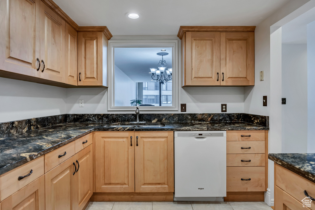 Kitchen with dishwasher, a sink, dark stone countertops, a chandelier, and light brown cabinetry