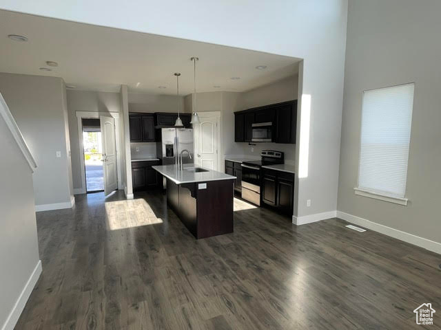 Kitchen with stainless steel appliances, a sink, open floor plan, light countertops, and recessed lighting