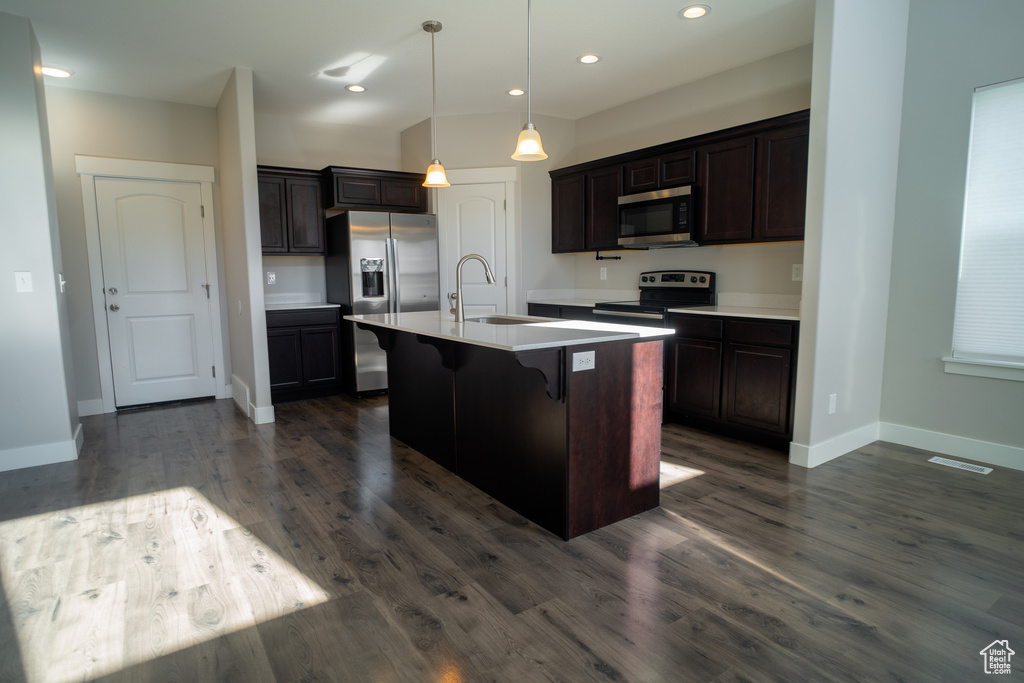 Kitchen featuring appliances with stainless steel finishes, a sink, baseboards, a kitchen breakfast bar, and dark wood-style floors