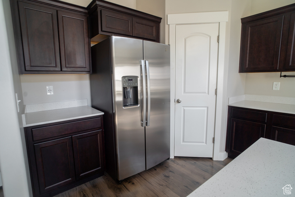 Kitchen with stainless steel refrigerator with ice dispenser, dark wood-type flooring, and dark brown cabinetry
