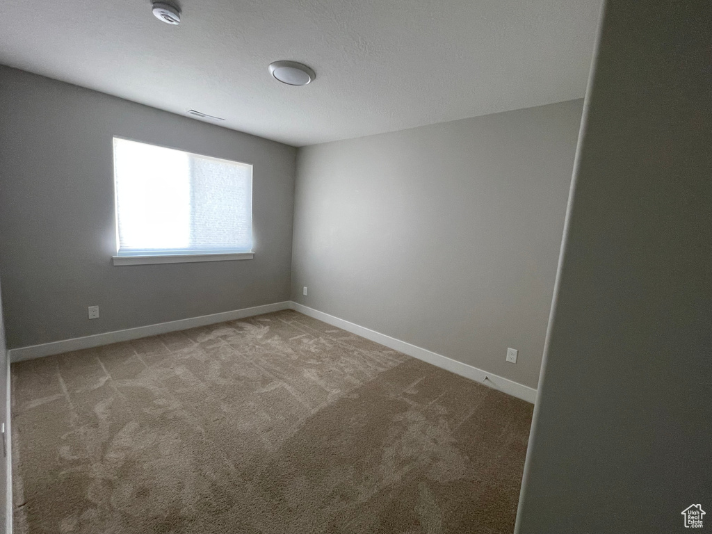 Carpeted spare room with baseboards and a smoke detector