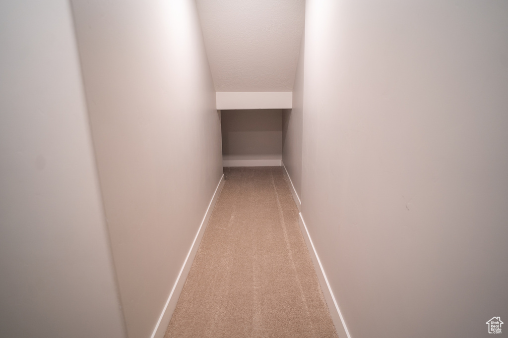 Hallway with light carpet and baseboards
