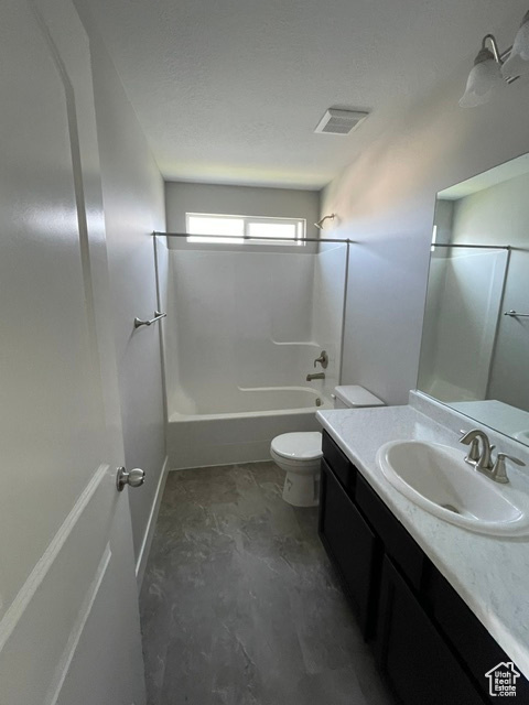 Full bath featuring vanity, toilet, washtub / shower combination, and concrete flooring