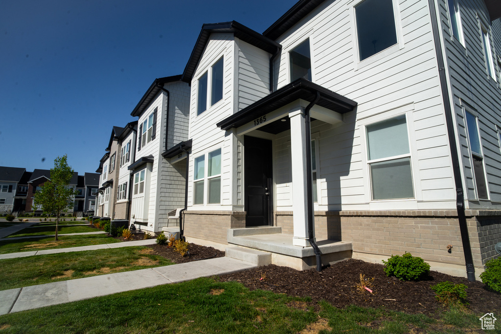 View of front of house featuring a residential view, brick siding, and a front lawn