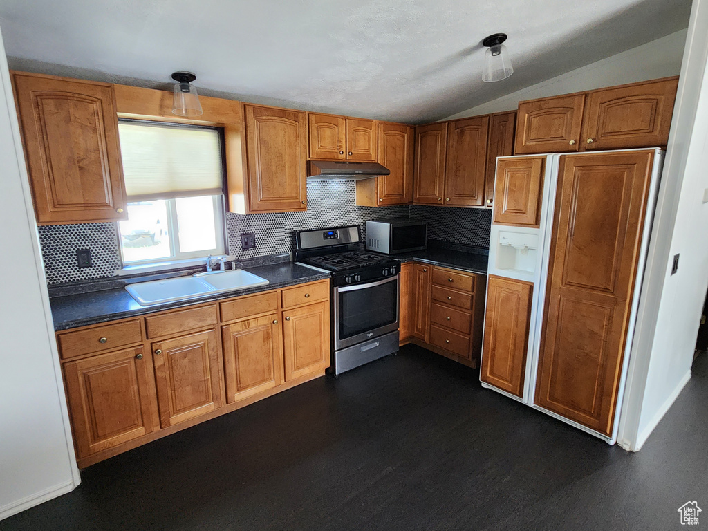 Kitchen featuring stainless steel appliances, a sink, dark wood-type flooring, vaulted ceiling, and decorative backsplash
