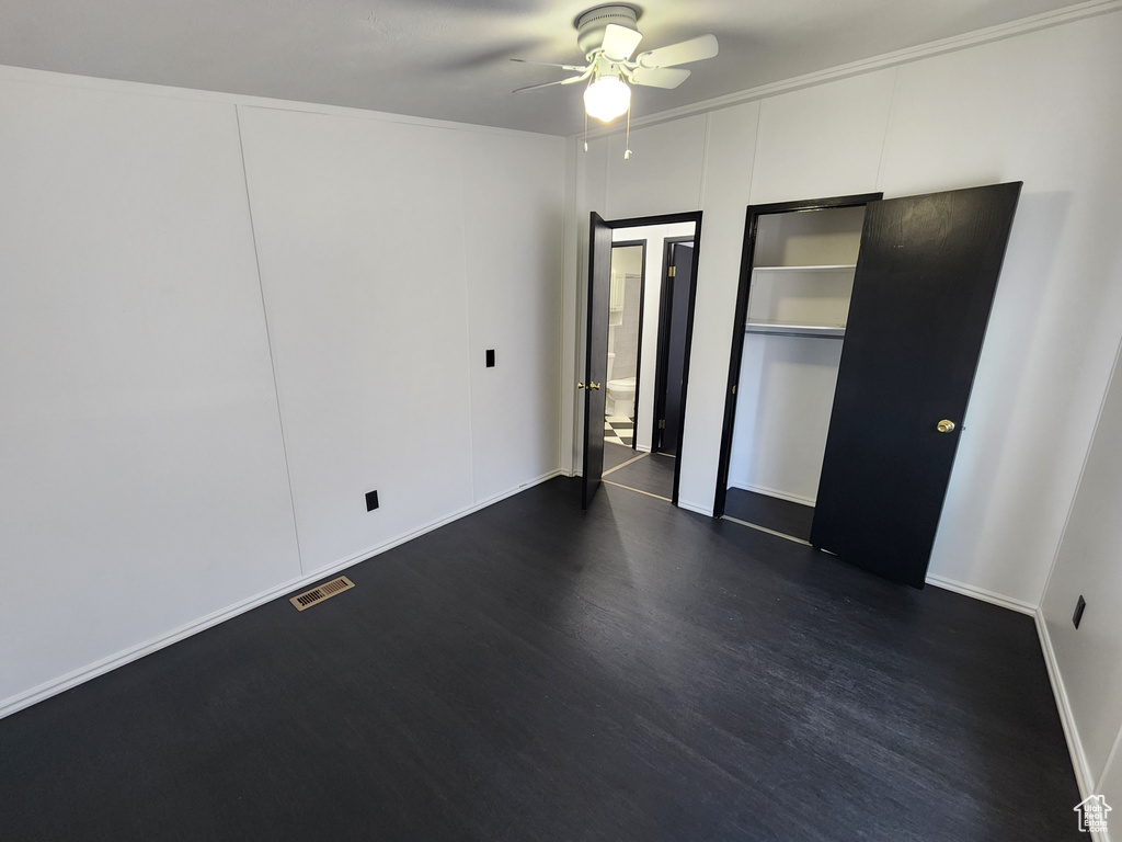 Unfurnished bedroom featuring dark wood-style floors, ceiling fan, and baseboards