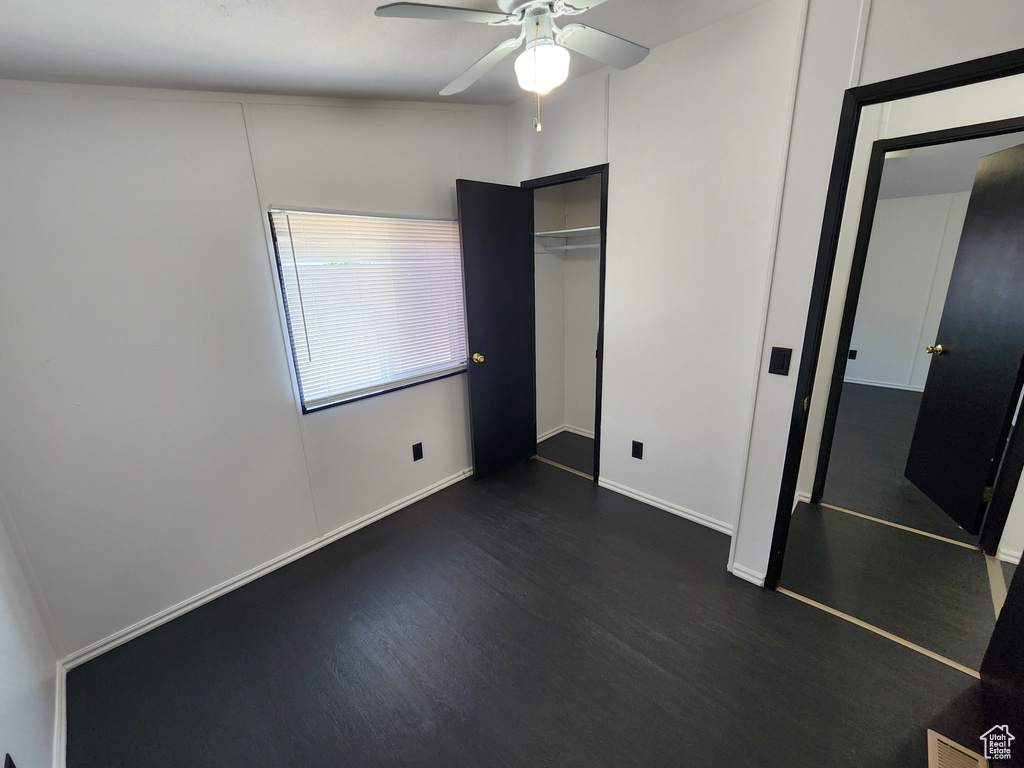 Unfurnished bedroom with dark wood-style floors, a closet, and baseboards