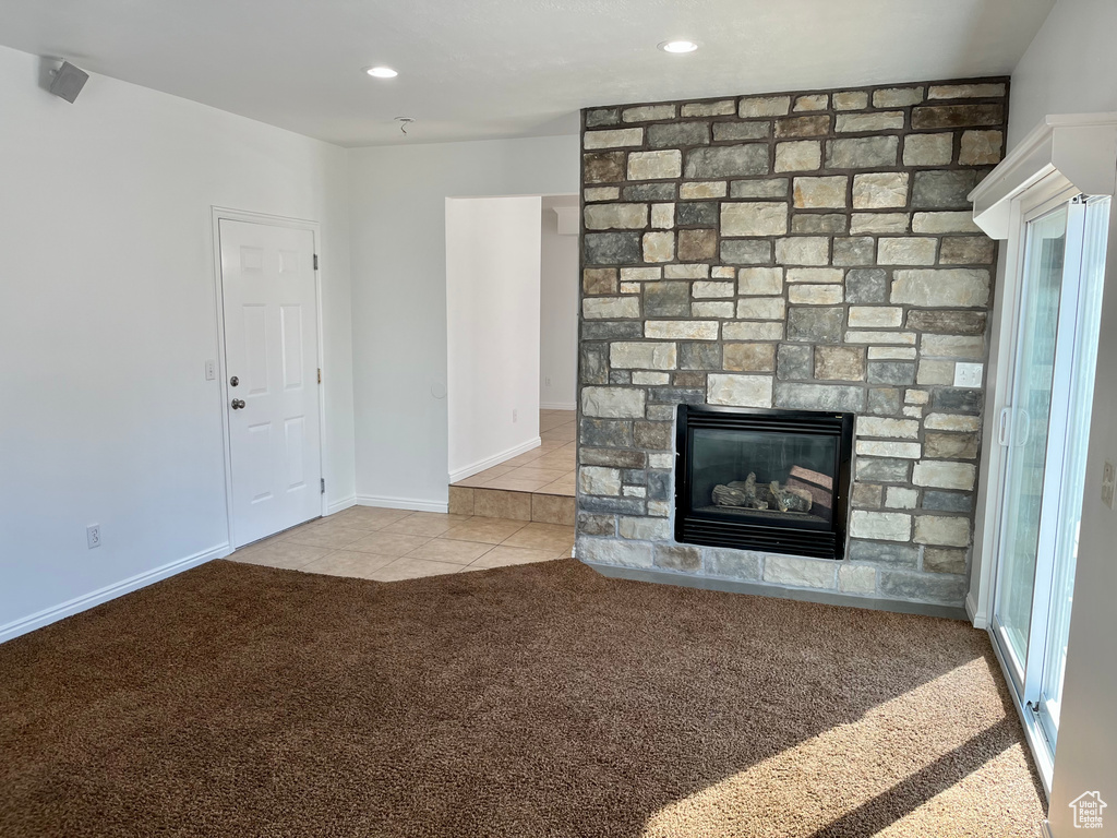 Unfurnished living room with carpet floors, a fireplace, tile patterned flooring, recessed lighting, and baseboards